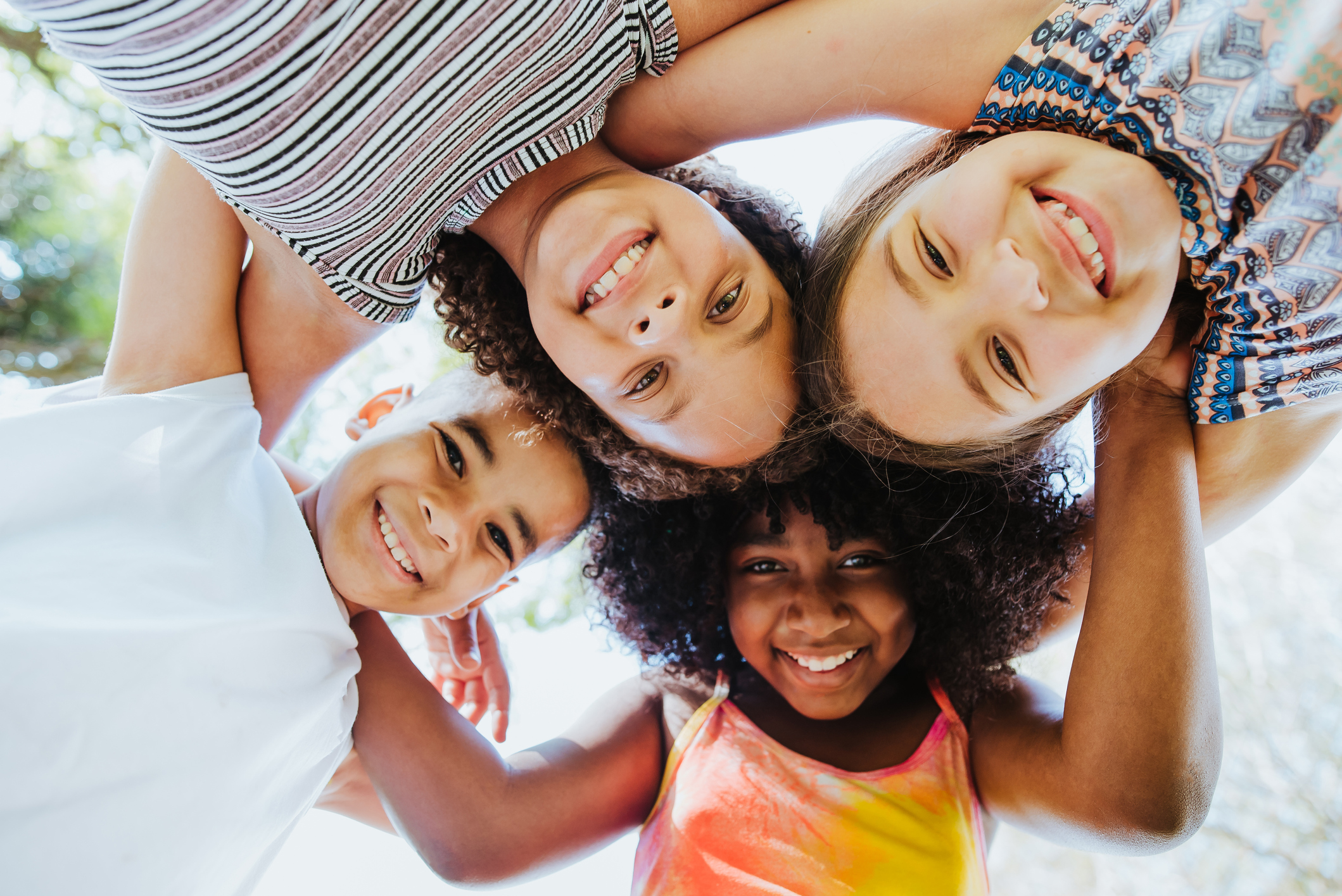 a group of youths are in a huddle with their arms wrapped around one another and smiling down at the camera